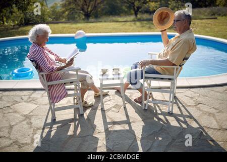 Senior man and woman enjoy on summer holiday near swimming pool together. Stock Photo