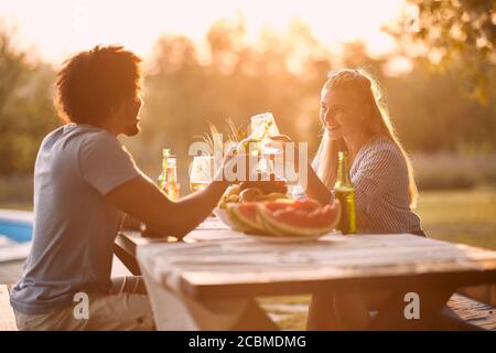 Multi-ethnic cheerful young  couple  drinking at dinner party. Stock Photo