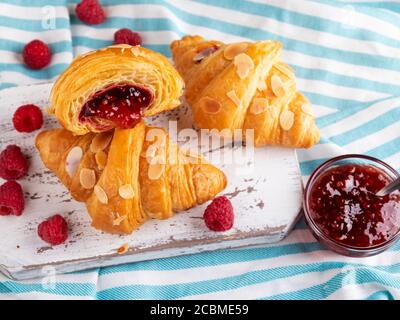 Yummy freshly croissant, with raspberries jam filling cut, close up Stock Photo