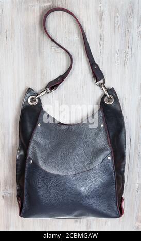 handcrafted gray leather handbag with big pocket on gray wooden table Stock Photo