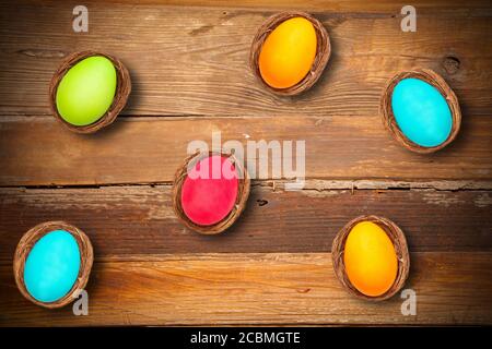 High angle shot of colorful Easter eggs in bird nests on a wooden surface Stock Photo