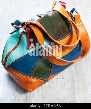 handcrafted patchwork leather travel bag on gray wooden table Stock Photo