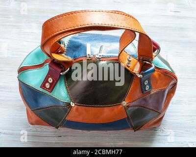 top view of handcrafted patchwork leather travel bag on gray wooden table Stock Photo