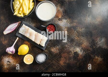 Raw cod fillet and other organic ingredients recipe fish and chips and beer batter, potatoe, shallotgarlic, salt, peppercorns on rustic metal textured Stock Photo