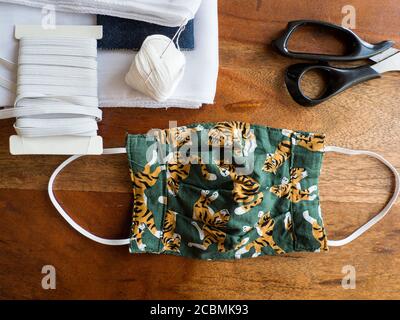 Handmade DIY patterned cotton mask for protection from Covid 19 (Corona Virus) with the sewing materials next to it. Stock Photo