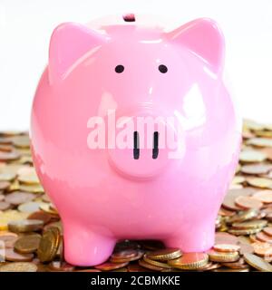 Closeup shot of a pink piggy bank surrounded by coins Stock Photo