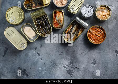 Assortment of cans of canned with different types of fish and seafood, opened and closed cans with Saury, mackerel, sprats, sardines, pilchard, squid Stock Photo