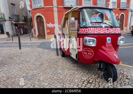 Tavira, Portugal - March 24, 2018: Cute red Tuk Tuk in the old town. Traditional three-wheel vehicles transport tourists to all famous attractions. Stock Photo