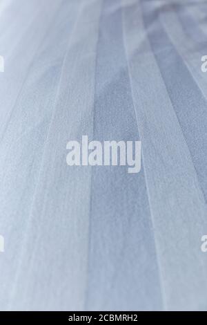 Close-up of a made, a bit wrinkled, clean striped white and light blue cotton bedsheet background. Shallow depth of field. Stock Photo