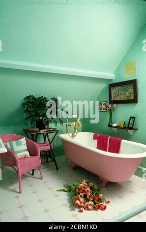 Free-standing bath in attic room with pink chair Stock Photo