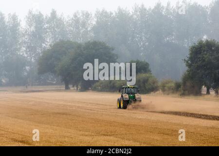 Disc harrowing a Norfolk field on a wet, misty evening after the harvest. Stock Photo