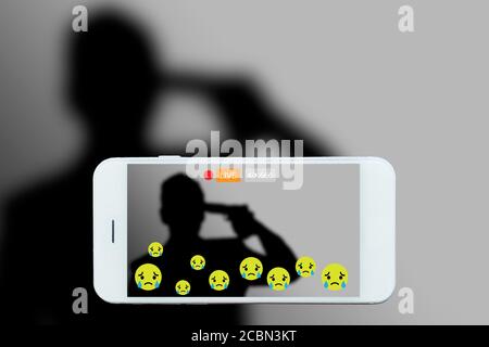 Problem of using social networks with wrong purpose effect concept:silhouette of man holding gun in hand stream his commits suicide stream live on soc Stock Photo