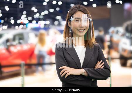 Portrait of Asian female car seller wearing face shield working while coronavirus pandemic Stock Photo