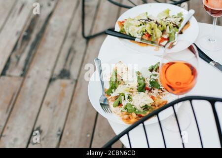 Homemade pizza and aperol drink on modern wooden terrace, dinner for two. Delicious pizza and cocktails for home celebration. Summer vacation and reso Stock Photo