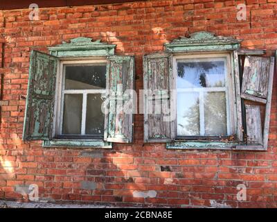 Wooden window. Old window with wooden shutters in a dilapidated house. Peeling paint on the shutters. Stock Photo