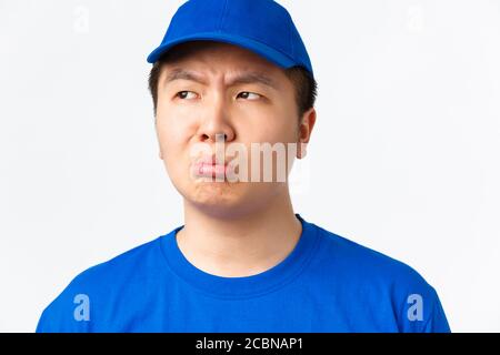 Online shopping, fast shipping, employees and home delivery concept. Close-up of sulking upset asian male courier in blue uniform, sobbing and Stock Photo