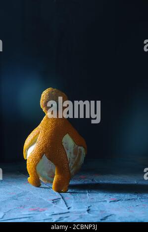 human figure from orange peel carries away peeled orange Stock Photo