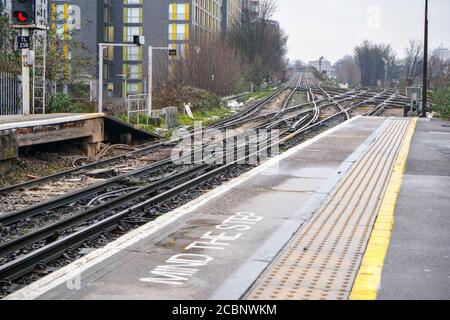 End of platform on train station at London, Mind the step written down, many railway crossings in distance Stock Photo