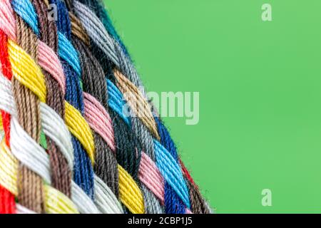 strip of braided colored cotton threads with green background Stock Photo