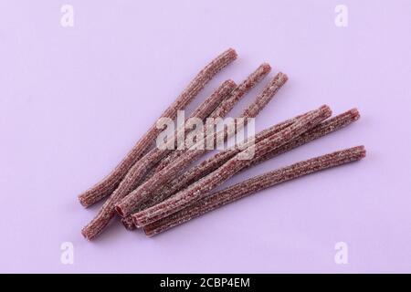Sour blueberry fruit flavored gummy candy sticks on lavender background Stock Photo