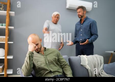 Grandfather Having Conflict With Father While Sad Son Sitting On Couch Stock Photo