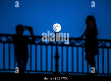 Couple taking pictures under moonling on the Triana bridge, Seville, Spain.