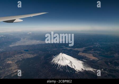 Aerial high angle top view of Mount Fuji, snow, sky and clouds. View from airplane. Highest volcano mountain in Japan. Stock Photo