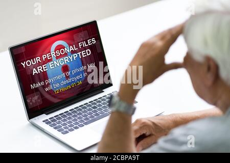 Elder Man With Ransom Text On Laptop Monitor After Ransomware Cyber Attack Stock Photo