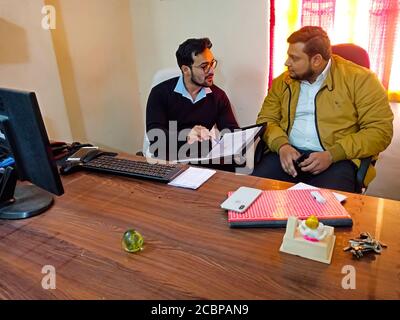 DISTRICT KATNI, INDIA - MARCH 18, 2020: Two indian office executive discussing together about file matter on table talk. Stock Photo