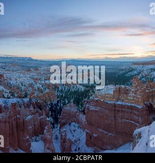 Rock formation amphitheater at sunrise, snowy bizarre rock landscape with hoodoos in winter, Rim Trail, Bryce Canyon National Park, Utah, USA Stock Photo