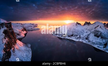 Aerial view, dramatic cloud atmosphere over the Nordfjorden, Bergsbotn, sun sinks into the sea behind snow-covered peaks of Luttinden, Senja Island Stock Photo