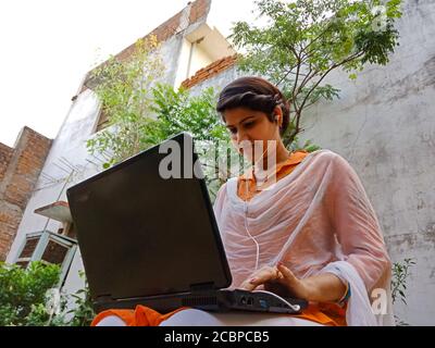 DISTRICT KATNI, INDIA - MAY 16, 2020: An indian corporate girl working on laptop, work from home at garden. Stock Photo