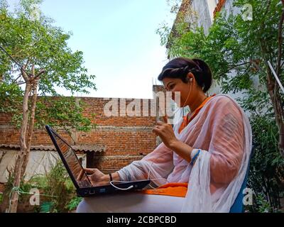 DISTRICT KATNI, INDIA - MAY 16, 2020: An indian corporate girl working on laptop, work from home at garden. Stock Photo