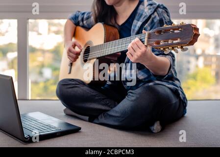 Woman learning online how to play guitar Stock Photo