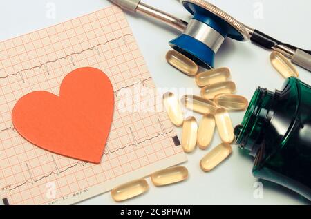 Medical stethoscope, tablets and heart shape on electrocardiogram graph. Medicine and healthy lifestyles. Ekg heart rhythm Stock Photo