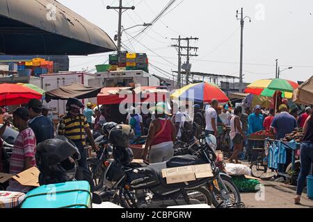Cartagena Columbia busy outdoor market shoppers motorcycles. 5057. Historical poor neighborhood outdoor market. Raw fresh meat, beef, pork and fish prepared in hot unsanitary conditions. Dirty, smelly environment with rotten food. Local restaurants and shopping. Stock Photo