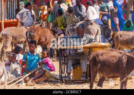 Emfraz, Ethiopia - January 17, 2019. Man mending clothes with a vintage manual sewing machine at the market in Emfraz. Stock Photo