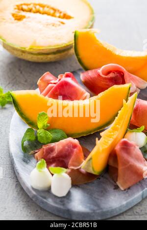Traditional Italian appetizer - Prosciutto with cantaloupe melon, mozzarella, basil and mint Stock Photo