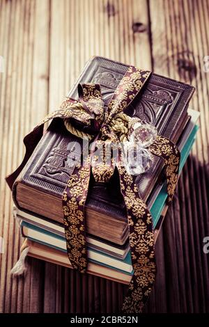 Stack of old books with vintage ribbon as present on wooden background Stock Photo
