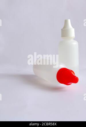 Two small white bottles with one white cap and one with red cap on white background. Stock Photo
