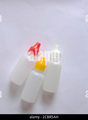 Three small white bottles with white, red and yellow cap on white background. Stock Photo