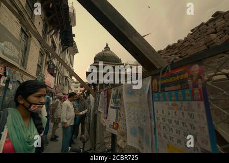 A pedestrian paying attention to printed calendars being displayed for sale at an alley in Durbar Square area, Kathmandu, Nepal. Stock Photo