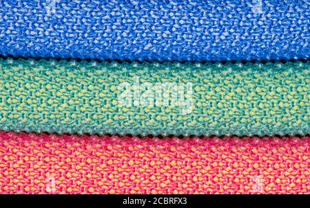 Three colored dishwashing scouring pads stacked up horizontally, blue green and red. Full frame abstract macro image with copy space. Stock Photo