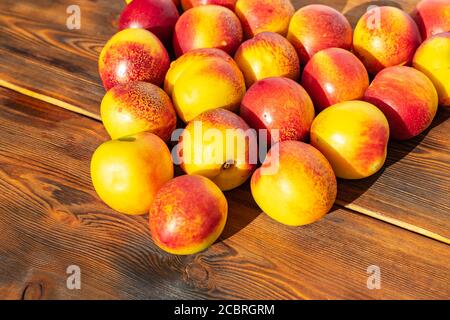nectarines on wooden brown background in harsh sunlight Stock Photo