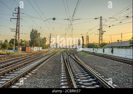 Railroad switch lines diverging in different directions at the station in the evening at sunset. Stock Photo