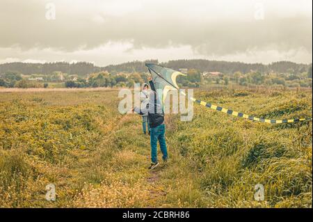 schoolboy and his mother launches a kite into the air in a field Stock Photo