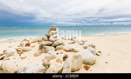 Stacked stones over the sea at sunset. Balanced stones stacked to a tower on the beach, clouds with dramatic sky Stock Photo