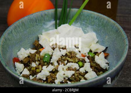 Closeup of bowl with greek snack: Fried minced meat, rice, paprika, sheep cheese and yogurt (focus on center) Stock Photo