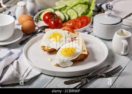Fried eggs with cheese and tomatoes on a croissant on a white plate. Morning food still life. Tasty breakfast Stock Photo