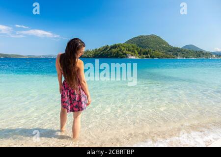 A woman wades in shallow clear water at Nidri Beach, Lefkada, Ionian Islands Greece